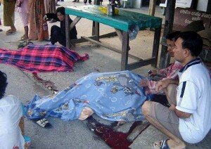 Buddhist villagers sit next to the dead bodies of their relatives in Pattani Thailand on Feb 3, 2011