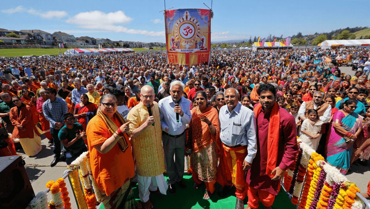 Three women standing in front of a presentation slide that says "United in Dharma, Diverse in Expression. Hindu Unity Day."