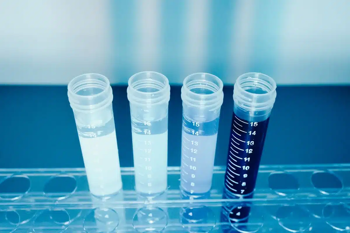 Laboratory technician handling a sample vial with genomic sequencing equipment in the background