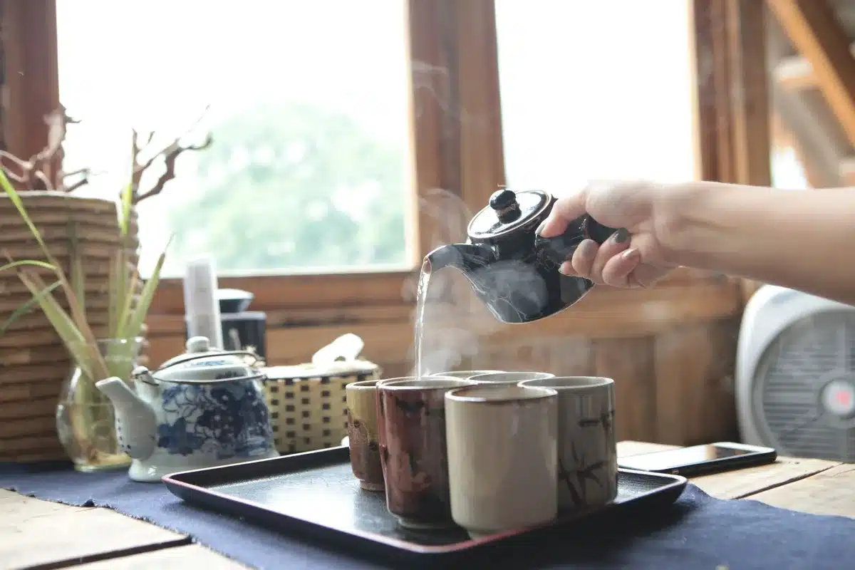Steaming masala chai being poured into cups at a café counter