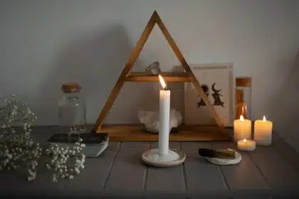 Person meditating before a lit altar with candles and ritual objects during spiritual practice