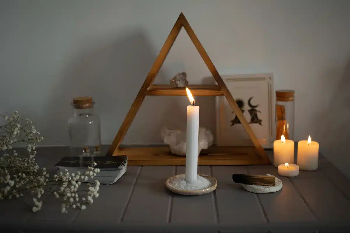 Person meditating before a lit altar with candles and ritual objects during spiritual practice
