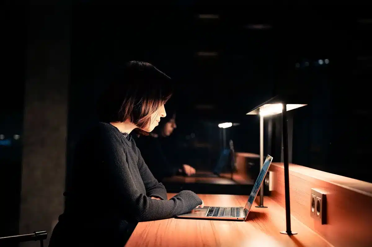 Mitternächtliche Videokonferenz: Ein Arbeitnehmer sitzt am Schreibtisch, während der Bildschirm ein Videomeeting zeigt.