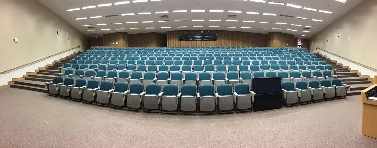 Auditorium seating with silhouettes of audience members in dim light