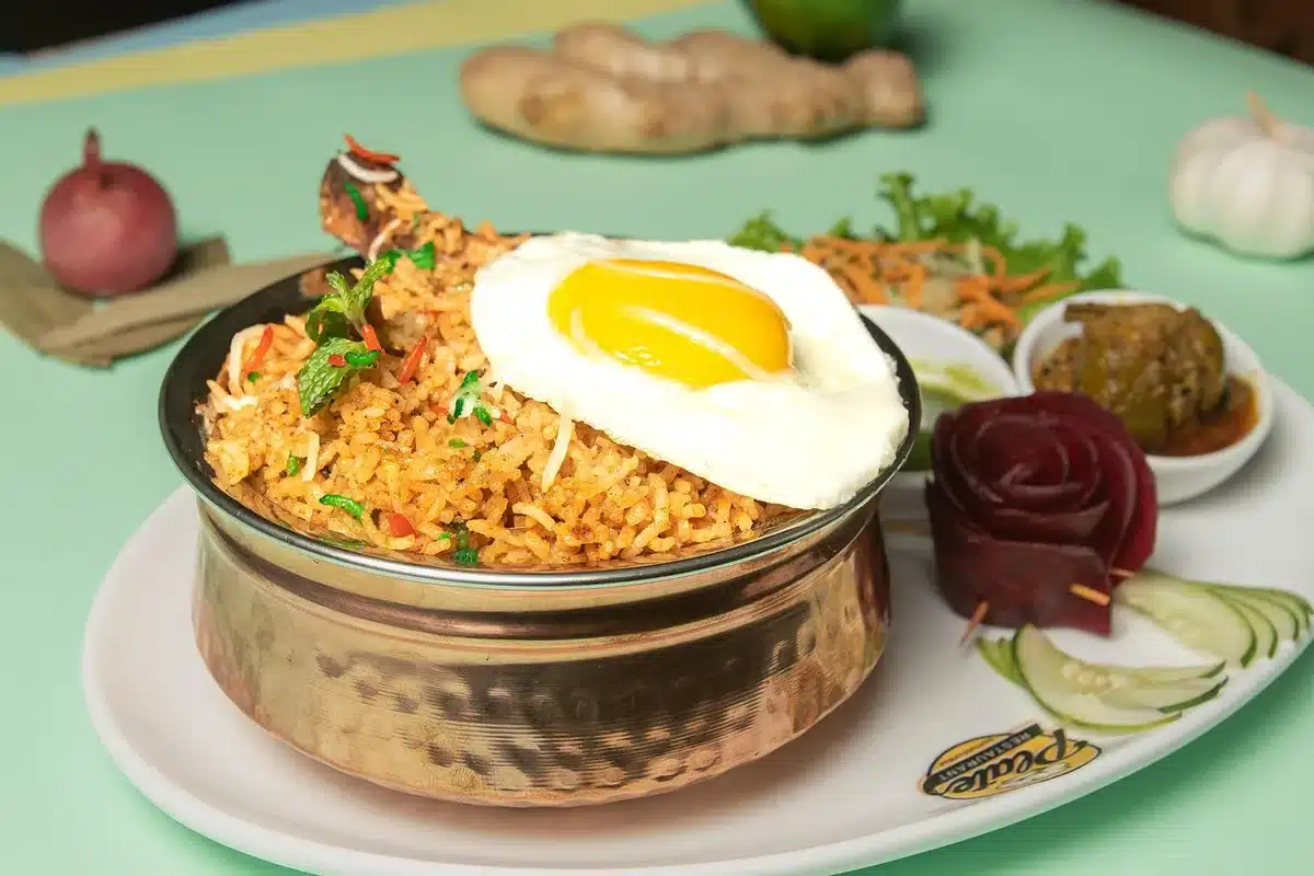 Anonymous hands using a spoon to lift rice from a plate of biryani in a casual diner