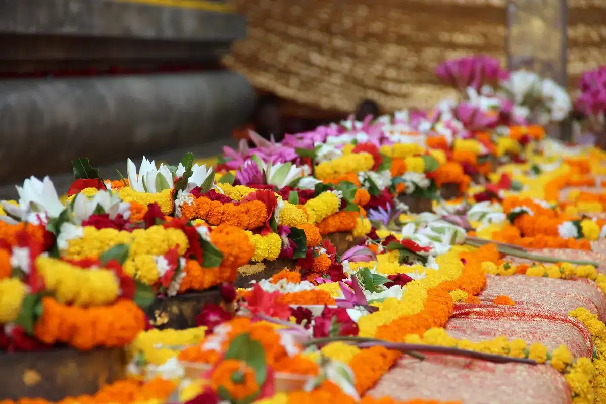 Hands arranging clay lamps and marigolds on an earthen altar