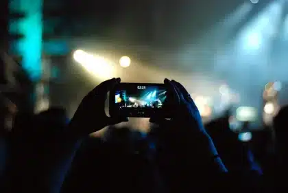 Hands holding a phone with blurred reaction icons and a meditation mala nearby